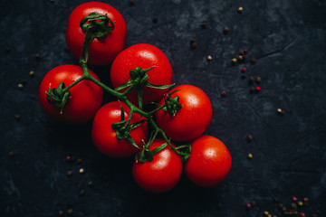 Flat lay of fresh tomatoes on branch isolated on black texture background. Close up. Ripe vegetables