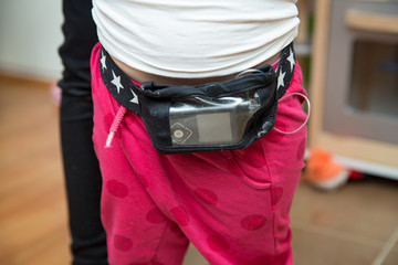 Little child having the diabetic insulin pump on belt connected to buttock. Glucose monitoring system. Diabetes treatment for kids - obrazy, fototapety, plakaty