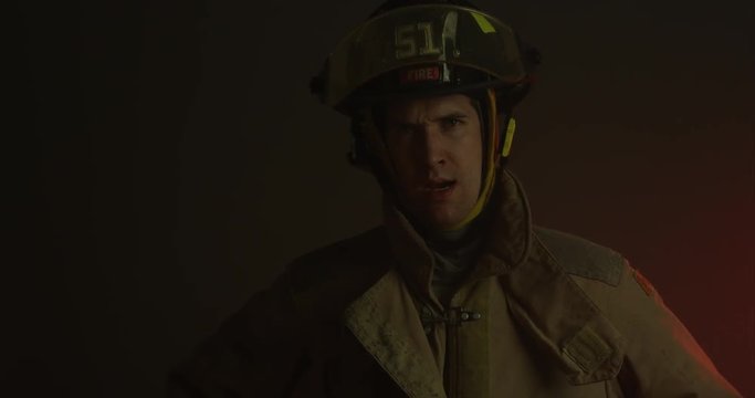 Firefighter unbuttons coat and puts hands on hips - exhausted - medium shot