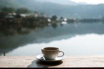 A Cup of coffee  on a rustic wooden table with village blurred background.