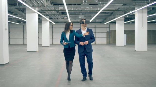 A man wears VR glasses while working with a businesswoman, modern technology.