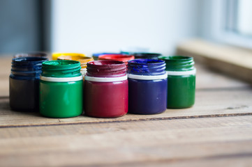 Plastic cans of paint and gouache. Art tools. The art and craft. Closeup. Wooden background.
