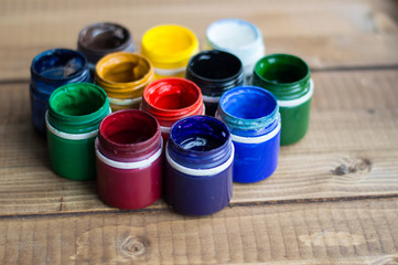 Plastic cans of paint and gouache. Art tools. The art and craft. Closeup. Wooden background.