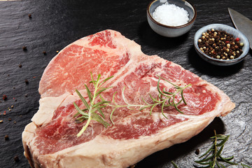 Raw T-bone steak on stone cutting board.