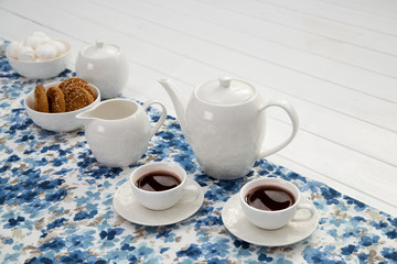 cups of coffee with milk, cream and biscuits on wooden white table