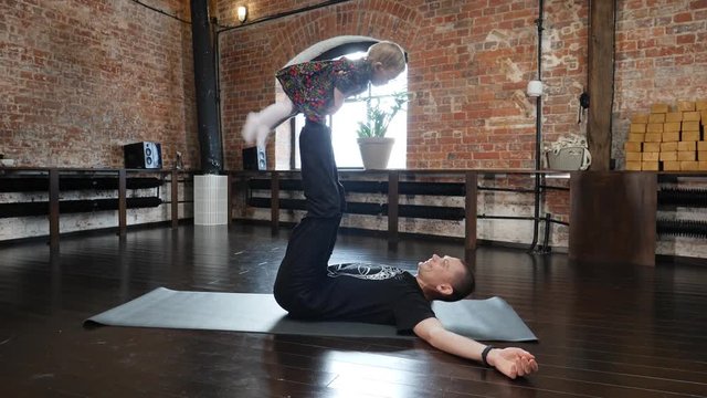 Acro yoga studio father practice a pose with his little child baby daughter