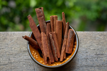 Cinnamon sticks in a bowl on wooden table.