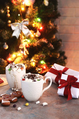 hot chocolate with marshmallow on table with christmas tree lights background
