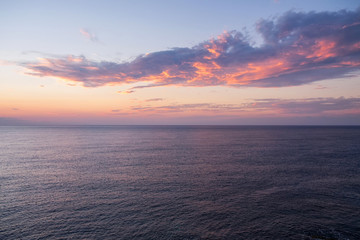 Dramatic sunset seascape with purple cloud floating above the calm sea