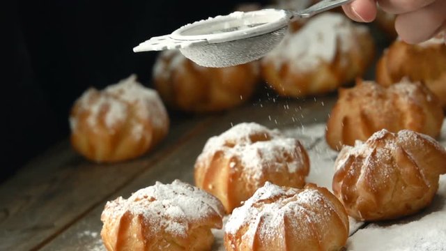 Sprinkling sugar powder over profiterole