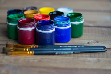 Plastic cans of paint and gouache. Art tools. The art and craft. Closeup. Wooden background.
