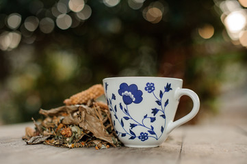 Tea in the white glass with a blue pattern near the handful of dried herbs