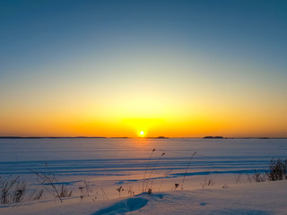Orange sunset in the winter on the river. Winter sunset landscape on the horizon.