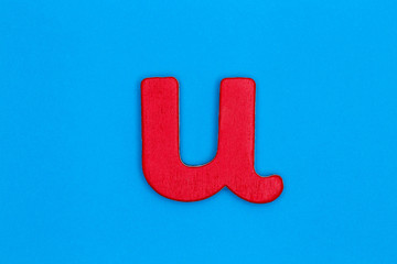 Wooden letter u painted red on a blue background
