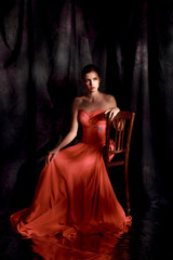 Beautiful woman in red evening dress on dark background