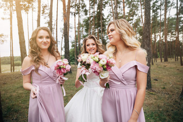 Wedding bouquet in hands. Beautiful bride with her pretty bridesmaids.