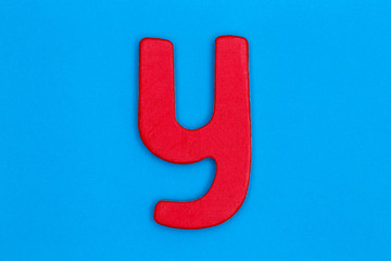 Wooden letter y painted red on a blue background
