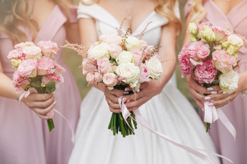 Wedding bouquet in hands. Beautiful bride with her pretty bridesmaids.