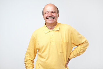 Mature adult man laughing looking at the camera over white background.