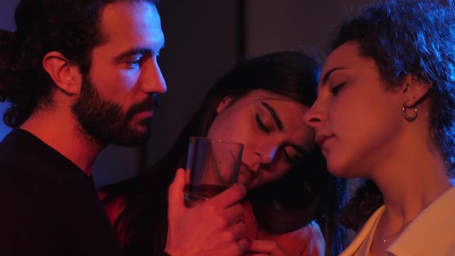 one man and two women flirting,kissing  in club at night.polyamory concept