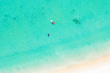 View from above, stunning aerial view of some tourist doing windsurfing and stand up paddle board on a beautiful clear and turquoise sea, Phi Phi Island, Thailand.