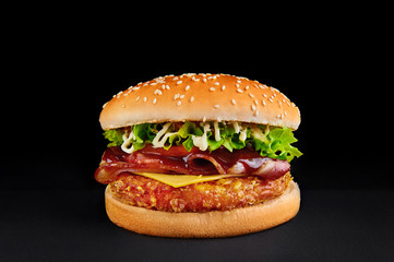 perfect burger with cutlet, cheese, bacon, tomato, lettuce isolated at black background