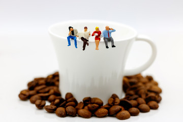 Miniature people: business team sitting on cup of coffee with morning news. Coffee time of business concept.