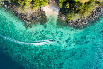 View from above, aerial view of a traditional long-tail boat sailing near a stunning barrier reef...