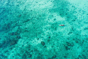 View from above, stunning aerial view of a traditional long-tail boat sailing on a turquoise and clear sea, Maya Bay, Thailand.