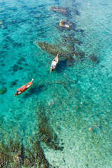 Fototapeta na wymiar View from above, stunning aerial view of some long-tails boats and tourists who do snorkeling in a beautiful, transparent and turquoise sea, Phi Phi Island, Thailand.