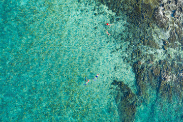 View from above, stunning aerial view of some tourists who do snorkeling in a beautiful, transparent and turquoise sea, Phi Phi Island, Thailand.