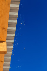 spring water drops flying from edge of barn roof with selective focus