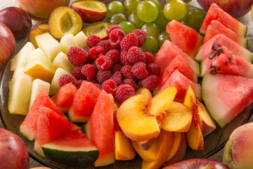 A mixture of their fruit. Peach, grapes, apple, watermelon, melon, raspberry, plum. Juicy and ripe pieces of fruit close-up. View from the top, Flat Lay.