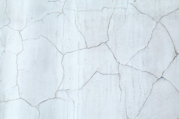 Gray concrete wall covered cracked plaster. Cracks on the wall resemble a map of the world with the borders of States