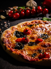 Traditional Italian pizza, vegetables, ingredients on a dark background. Pizza is cooking in the oven. Pizza menu.