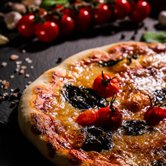 Traditional Italian pizza, vegetables, ingredients on a dark background. Pizza is cooking in the oven. Pizza menu.