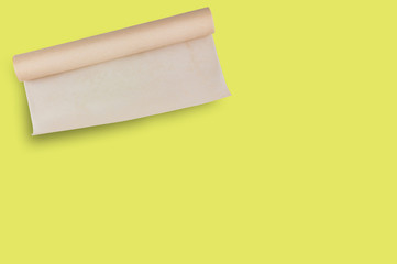 One roll of brown baker paper on yellow table on cuisine with copy space for your text. Top view. Flat lay. Cooking concept