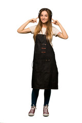 Full body Young woman with apron listening to music with headphones on isolated background