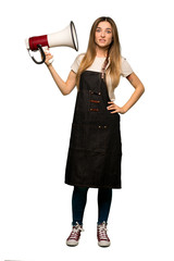 Full body Young woman with apron taking a megaphone that makes a lot of noise on isolated background
