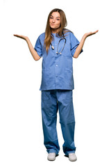 Full body Young nurse having doubts while raising hands and shoulders on isolated background