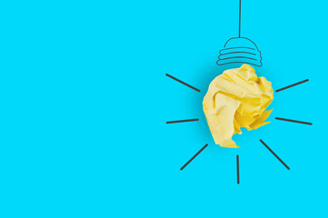 One crumpled yellow paper and image on blue table in office made light bulb. Top view. Inspiration concept. Copy space for your text