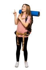 Full body Young backpacker woman pointing with the index finger and looking up on isolated background