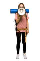 Full body Young backpacker woman shouting through a megaphone to announce something on isolated background