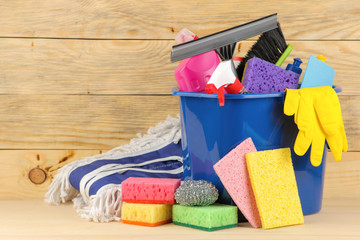 Bottles with detergent and cleaning tools in a bucket on a natural wooden background. cleaning. cleaning products. place for text. free place