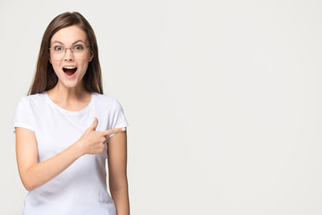 Excited teen girl pointing finger at copyspace isolated on background - obrazy, fototapety, plakaty
