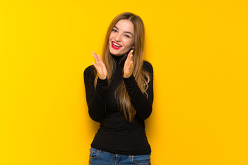 Young pretty woman over yellow background applauding after presentation in a conference