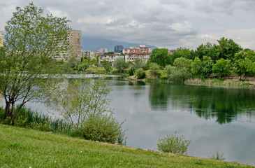 Spring panorama of a part of residential district neighborhood along a lake with green trees, shrubs and flowers, Drujba, Sofia, Bulgaria 