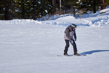 middle-aged man in equipment snowboarding on a mountain slope on a sunny day