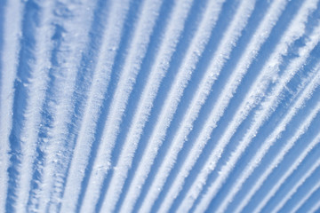 Texture of fresh stripped snowcat traces on snow. Deep furrows in the snow.