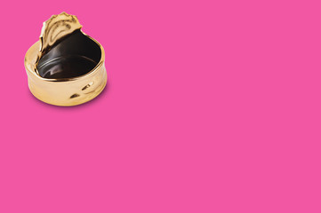 One empty golden ceramic ashtray for ash and cigarettes in form of opened tin can on pink table with copy space for your text